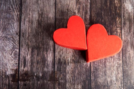 Two red paper hearts are next to each other on a wooden brown table. The day of Valentine. Copy space