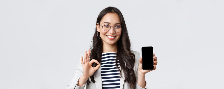 Business, finance and employment, female successful entrepreneurs concept. Close-up of stylish modern asian businesswoman introduce mobile app or advertisement, guarantee quality, show ok sign.