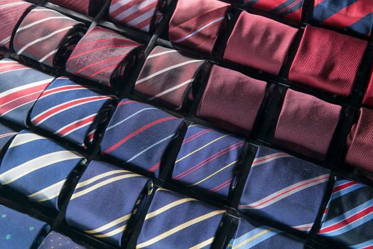 Men's silk ties are laid out from burgundy to blue in special compartments for ties