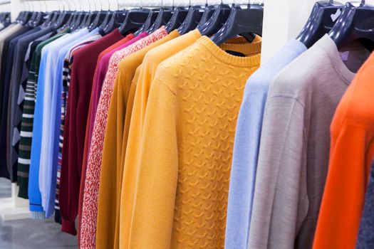 Women's multicolored knitted and crocheted sweaters, jackets hang on hangers in the store