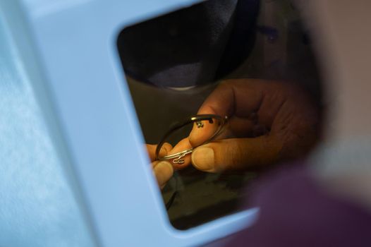 The technician solders the metal frame of the glasses