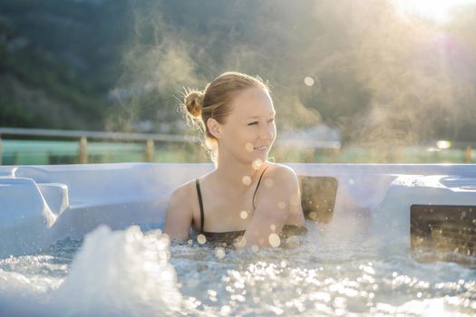 Portrait of young carefree happy smiling woman relaxing at hot tub during enjoying happy traveling moment vacation life against the background of green big mountains.
