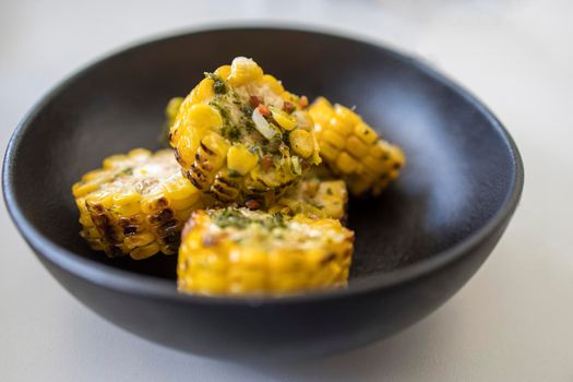 Chopped, grilled spiced corn in a black ceramic plate