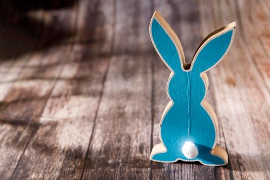 Blue hare on a wooden table. Easter decoration. Copy space