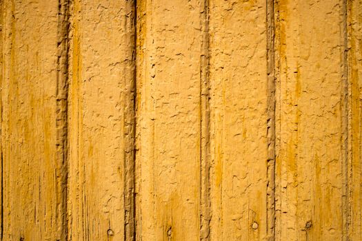 Texture of a yellow painted wall of wood planks with peeling paint