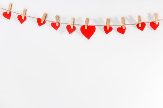 A handmade garland of the hearts is on a white wall. Place for text. Copy space