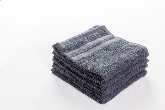 Spa set of grey towels on a white wooden background. Gift set, side view horizontal orientation. Concept of Spa treatments. Copy space