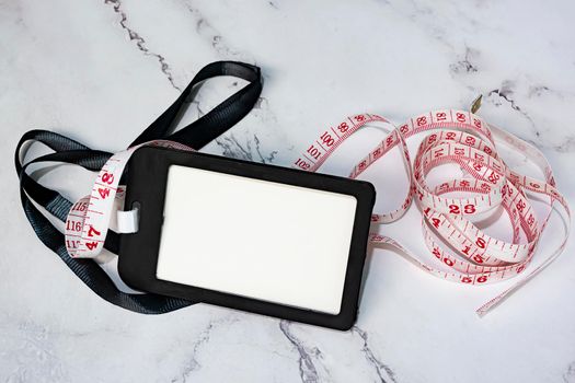 Black name tag with measure tap on white desk. Healthy and diet concept. Copy space.