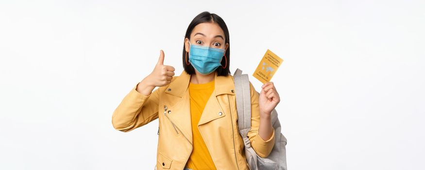 Hey you got point. Cheerful cute asian lively girl dark short haircut pointing camera finger-pistol smiling broadly, encourage friend make move, congratulate coworker good job, stand blue background.