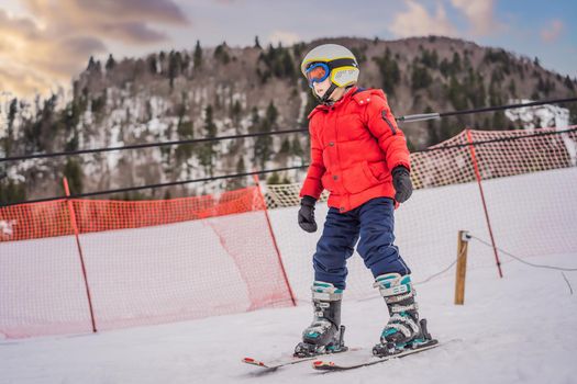 Child skiing in mountains. Active toddler kid with safety helmet, goggles and poles. Ski race for young children. Winter sport for family. Kids ski lesson in alpine school. Little skier racing in snow.