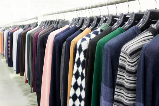 Women's multicolored knitted and crocheted sweaters, jackets hang on hangers in the store