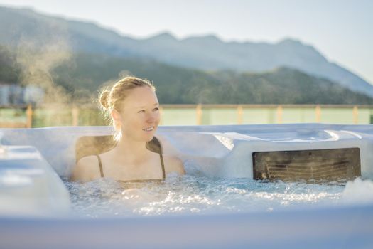 Portrait of young carefree happy smiling woman relaxing at hot tub during enjoying happy traveling moment vacation life against the background of green big mountains.