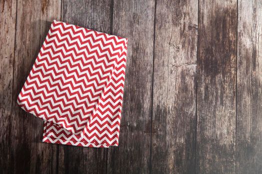 Kitchen towel napkin is on the brown wooden table. Top view. Maximum sharpness. knitted napkin in red and white zigzag. Copy space