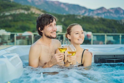 Portrait of young carefree happy smiling couple relaxing at hot tub during enjoying happy traveling moment vacation life against the background of green big mountains.