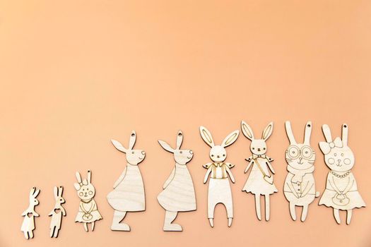 Family of funny hares cut out of plywood are on the yellow, orange, pink background. Card design. Copy space. Place for text