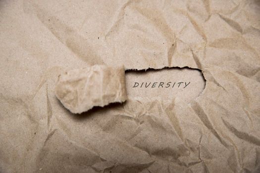 Uncovering a diversity. There is a hole in the craft paper, the word love is printed in it.