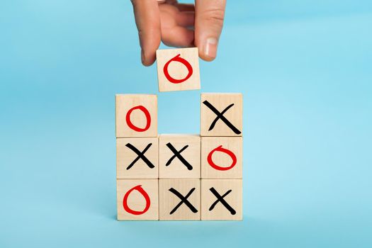 Wooden block tic tac toe board game. Business marketing strategy planning concept. Hand putting wooden cube block which print screen O to O and X game or tic-tac-toe elements.