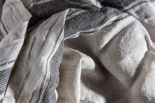 Linen gray striped towel rolled up lies on a wooden table