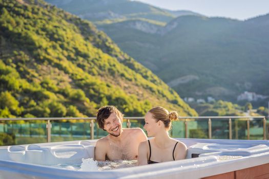 Portrait of young carefree happy smiling couple relaxing at hot tub during enjoying happy traveling moment vacation life against the background of green big mountains.