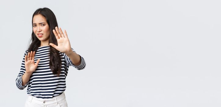 Lifestyle, beauty and fashion, people emotions concept. Woman feeling uncomfortable being photographed, asking turn camera off, raising hands up defensive, protecting face from flashlight.