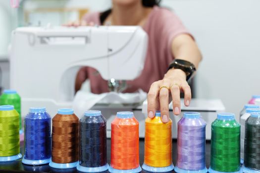 Embroidery, handicrafts, SME, family business Portrait of an Asian female designer picking up sewing threads for Design patterns using automatic embroidery machines according to customer orders