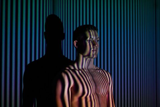 Studio shot of a young man posing against abstract lighting.