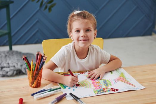 Cute little girl in art school draws her first paintings by pencils and markers.