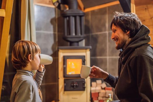 Dad and son spend time by the fireplace in Glamping. Rest in the mountains in Glamping. Cozy fireplace in a mountain house.