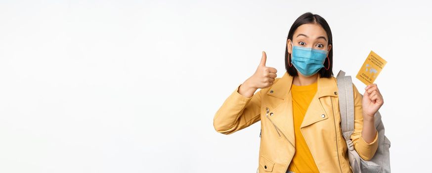 Hey you got point. Cheerful cute asian lively girl dark short haircut pointing camera finger-pistol smiling broadly, encourage friend make move, congratulate coworker good job, stand blue background.
