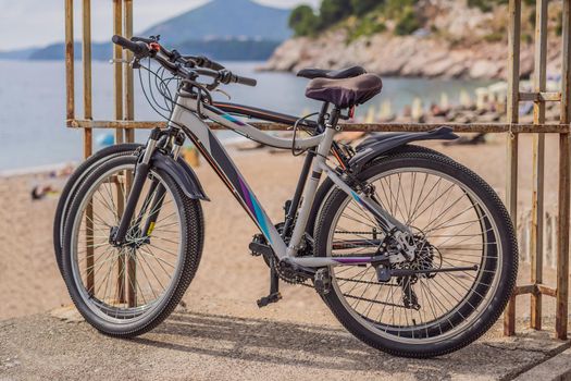 Bicycle stands at a metal railing against the background of the sea. A lady's bicycle is leaning against the shiny handrails. Cycling along the sea embankment.