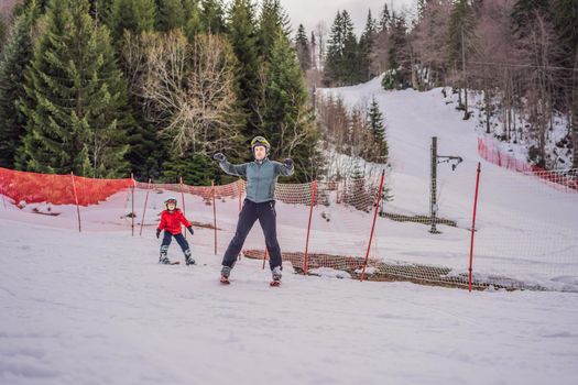 Boy learning to ski, training and listening to his ski instructor on the slope in winter.