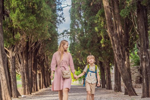 Mom and son tourists walking together in Montenegro. Panoramic summer landscape of the beautiful green Royal park Milocer on the shore of the the Adriatic Sea, Montenegro.