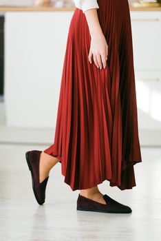 Photo of women's legs in a stylish suede burgundy loafers. Woman wearing red skirt