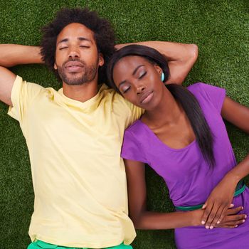 A young african couple lying on the grass together.