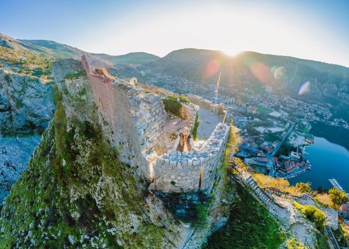 Young tourist woman enjoying a view of Kotor Bay, Montenegro. Kotor Old Town Ladder of Kotor Fortress Hiking Trail. Aerial drone view.