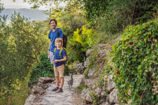 father and his son walking with a cat in a national park.