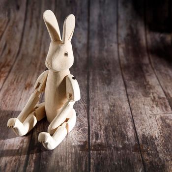 Raw wood hinged hare on a wooden table. Easter decoration. Copy space