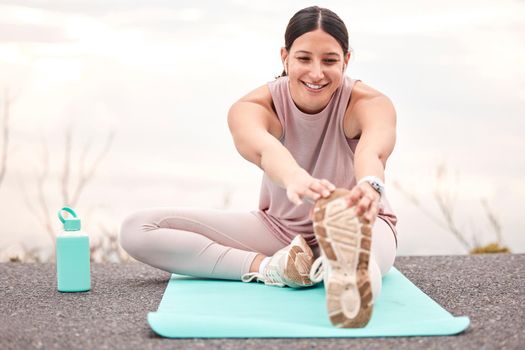 Shot of a young female athlete stretching before a run in nature.