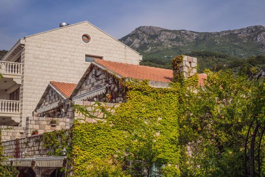 beautiful view of the mediterranean stone houses with a red tiled roofs and with balconies, the cozy yards, green trees, on a sunny summer day.