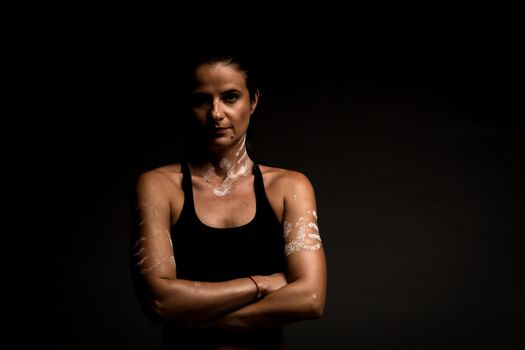 Portrait of a fit girl in sportsbra. Magnesium powder prints of hands on her body.