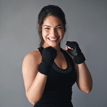 Studio shot of a female kickboxer against a gray background.
