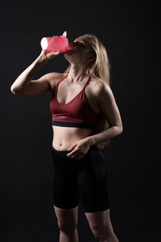 A pink shaker holds girl her fitness sex in hand in black background shaker pink fitness workout, from female woman for person and bodybuilding strength, beautiful people. Sweat ABS beauty