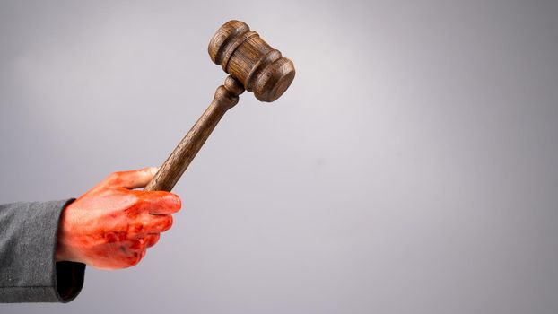 A female judge holds a gavel in a bloody hand on a white background. Copy space