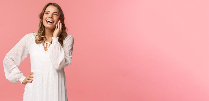 Portrait of carefree good-looking girl with blond short hair, wear white dress, laughing happy as talking on phone, hear funny joke, have conversation using mobile, hold smartphone and chuckle.