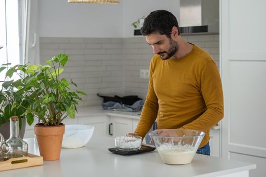 young bearded man making artisan bread in his home kitchen