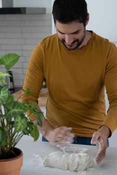 young bearded man making artisan bread in his home kitchen