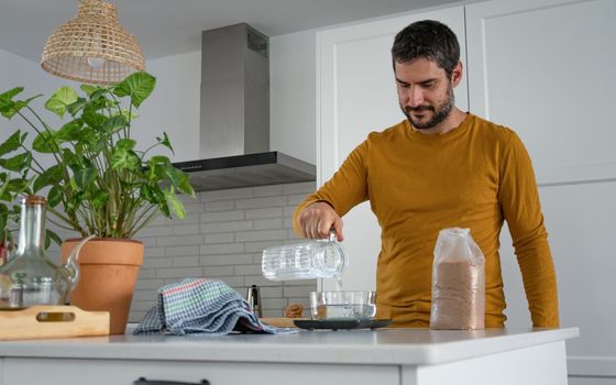 young bearded man making artisan bread in his home kitchen