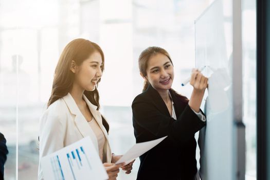 Business asian woman presentation conductor manager coach drawing writing plan on whiteboard presenting new corporate strategy.