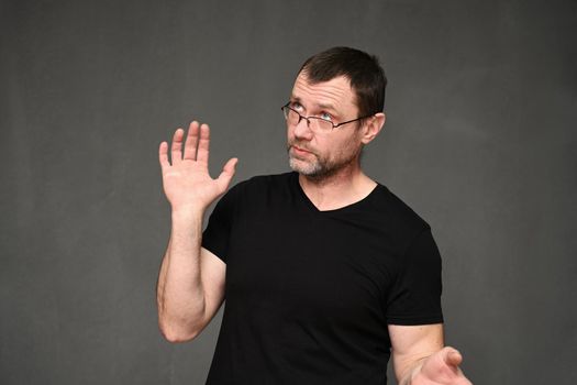 Adult caucasian man in glasses portrait in surprise on gray background