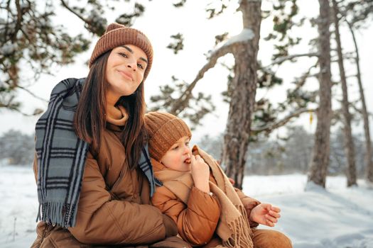 Woman with a little son on a winter hike in the snowy forest together